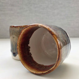 interior of handmade ceramic cup with speckled base and amber-brown rim