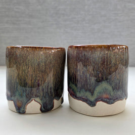 set of two handmade ceramic cups with a warm amber glaze blending into brown, maroon and green tones over a warm white base