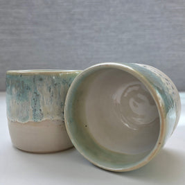 set of two handmade ceramic cups featuring a white interior with blue-green rim detailing