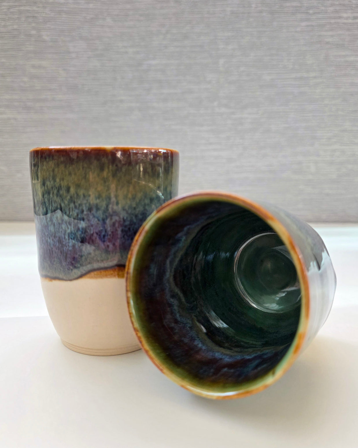 set of two handmade ceramic cups with an interior blending green, brown, blue, and amber tones