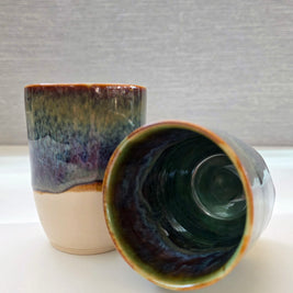 set of two handmade ceramic cups with an interior blending green, brown, blue, and amber tones