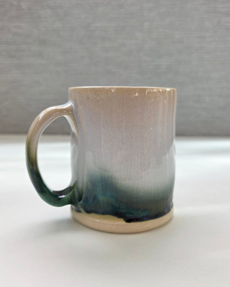 handmade ceramic mug with a handle, finished in a soft gradient glaze transitioning from warm white to a deep green base