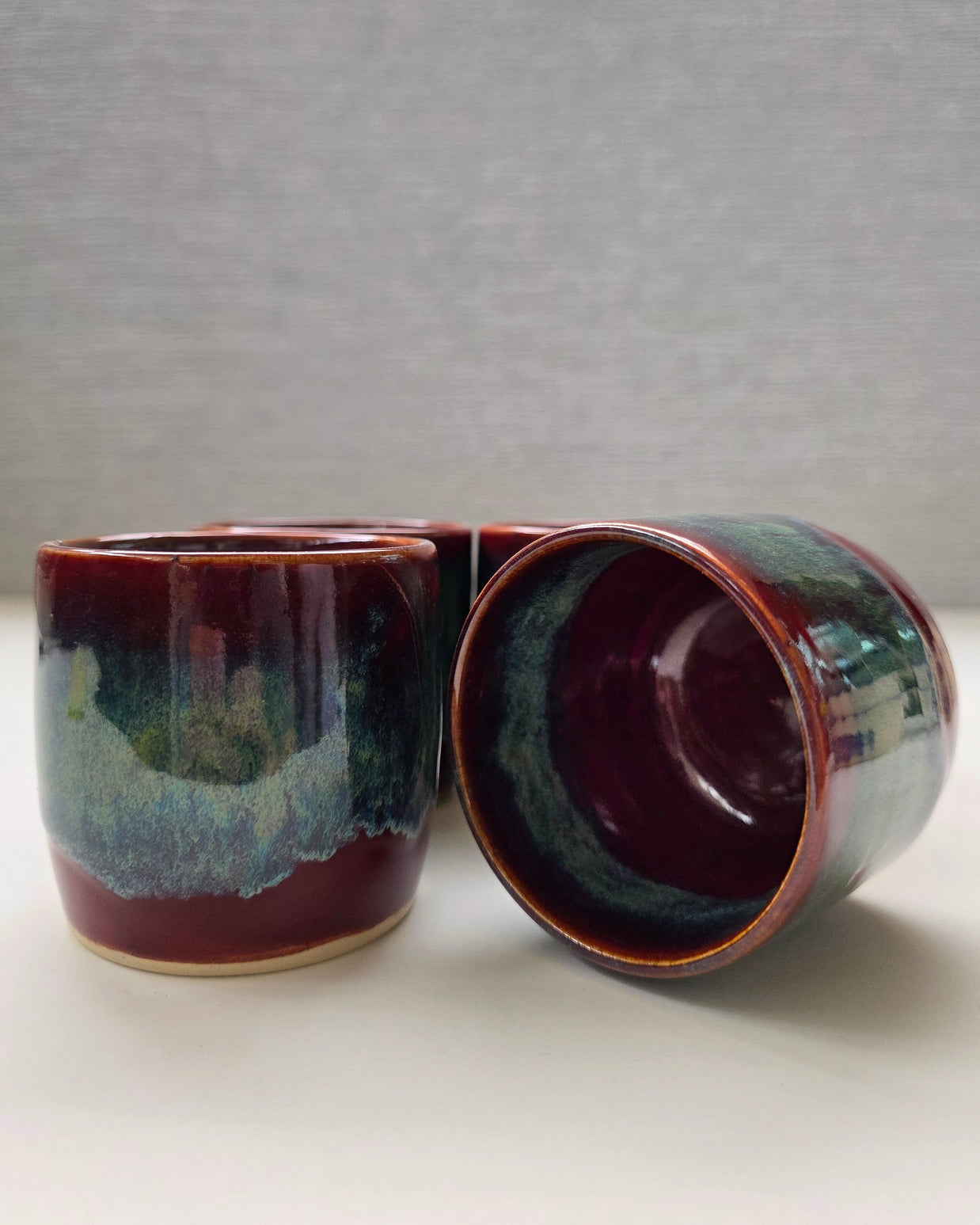 set of two handmade ceramic lungo cups with deep maroon glaze and teal wash detail